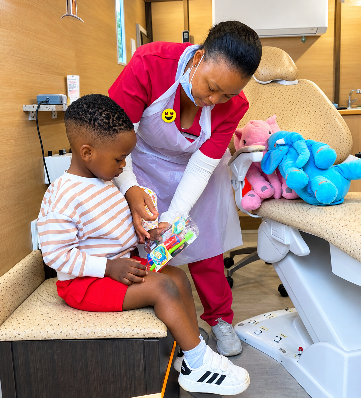 A dentist talks with a young boy sitting in a dental chair